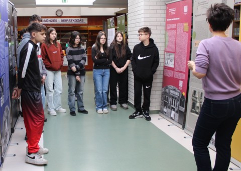 Középiskolai diákok meghallgatják a tárlatvezetést.